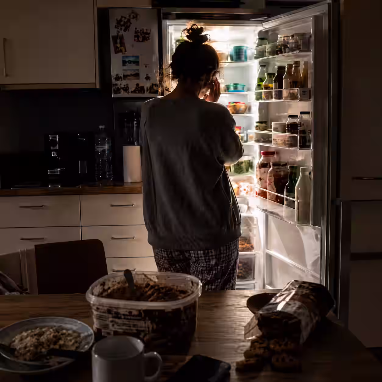 Donna davanti al frigorifero aperto di notte
